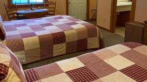 A bedroom with two beds, a desk, and a chair. There is a window with blinds, a door, and a mirror in the bathroom. - The Garrett Inn (Oakland)
