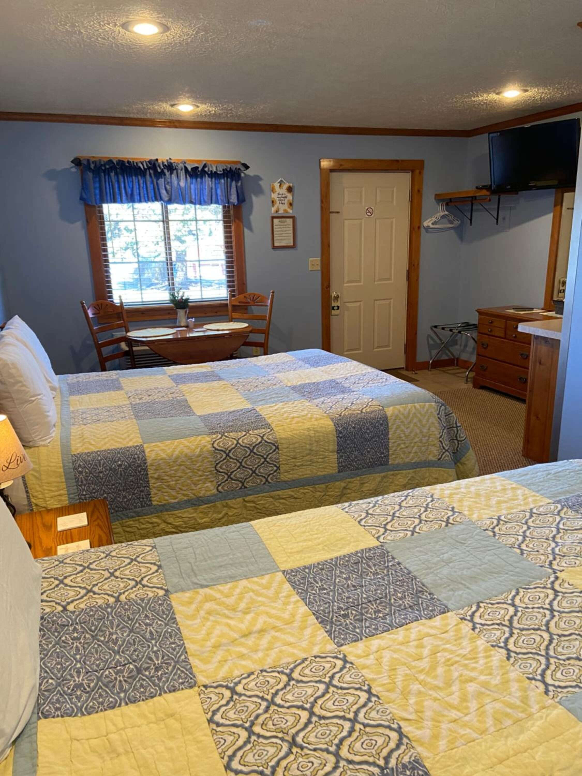 A bedroom with two beds, a desk, and a chair.