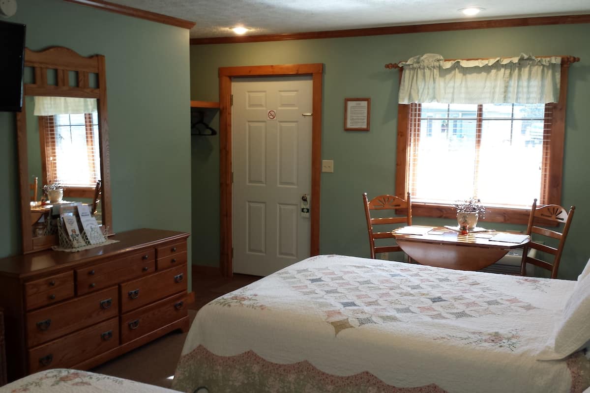 A bedroom with a bed, dresser, and a chair near a window.