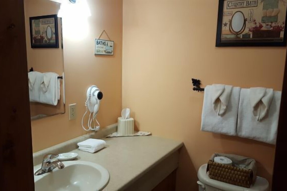 A bathroom with a sink, mirror, towel rack, and a toilet.