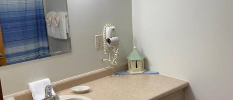 A bathroom with a sink, mirror, towel rack, and a framed sign above the mirror.