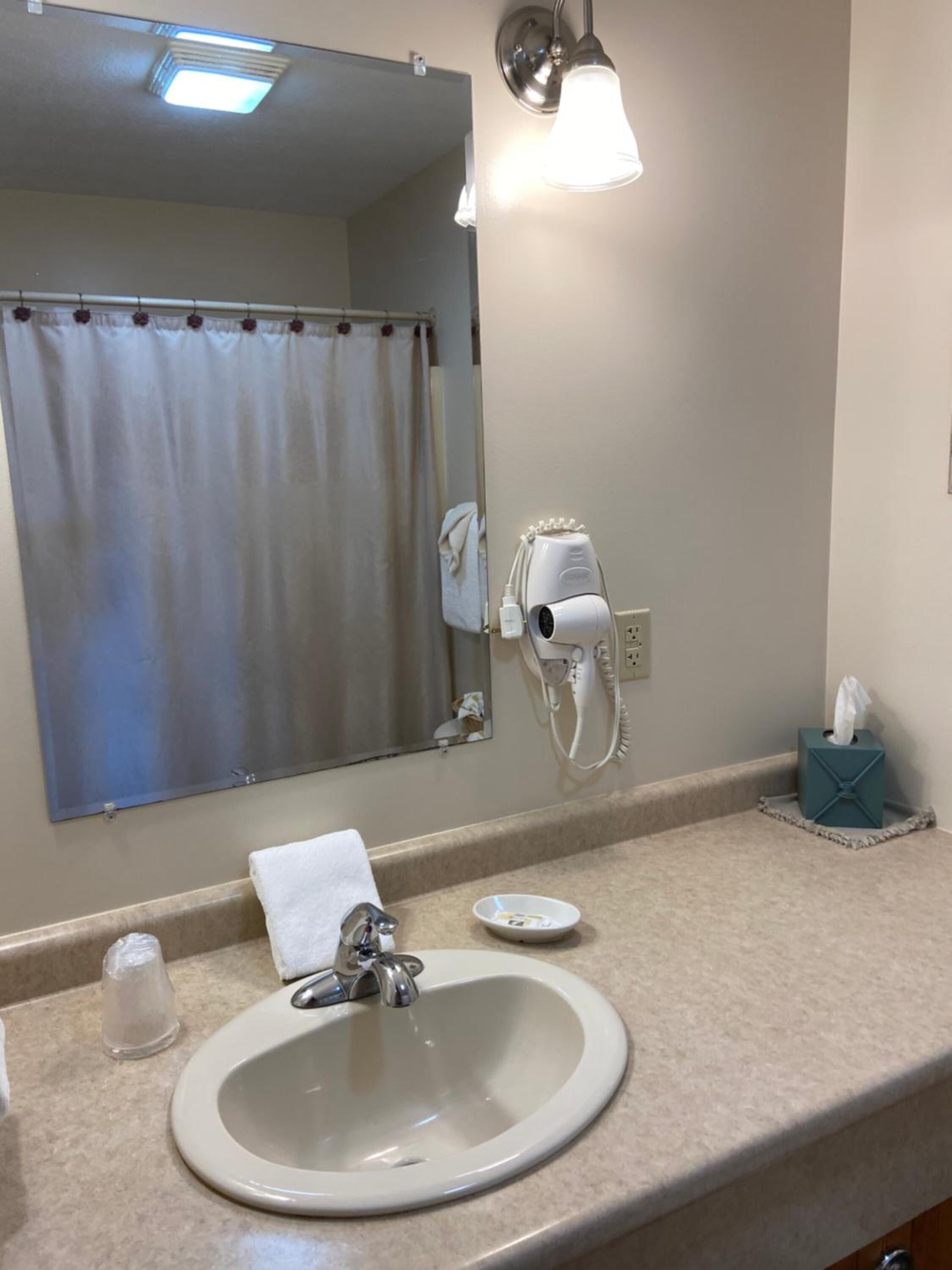 Une salle de bain équipée d’un lavabo, d’un miroir, d’un porte-serviettes et d’un sèche-cheveux.