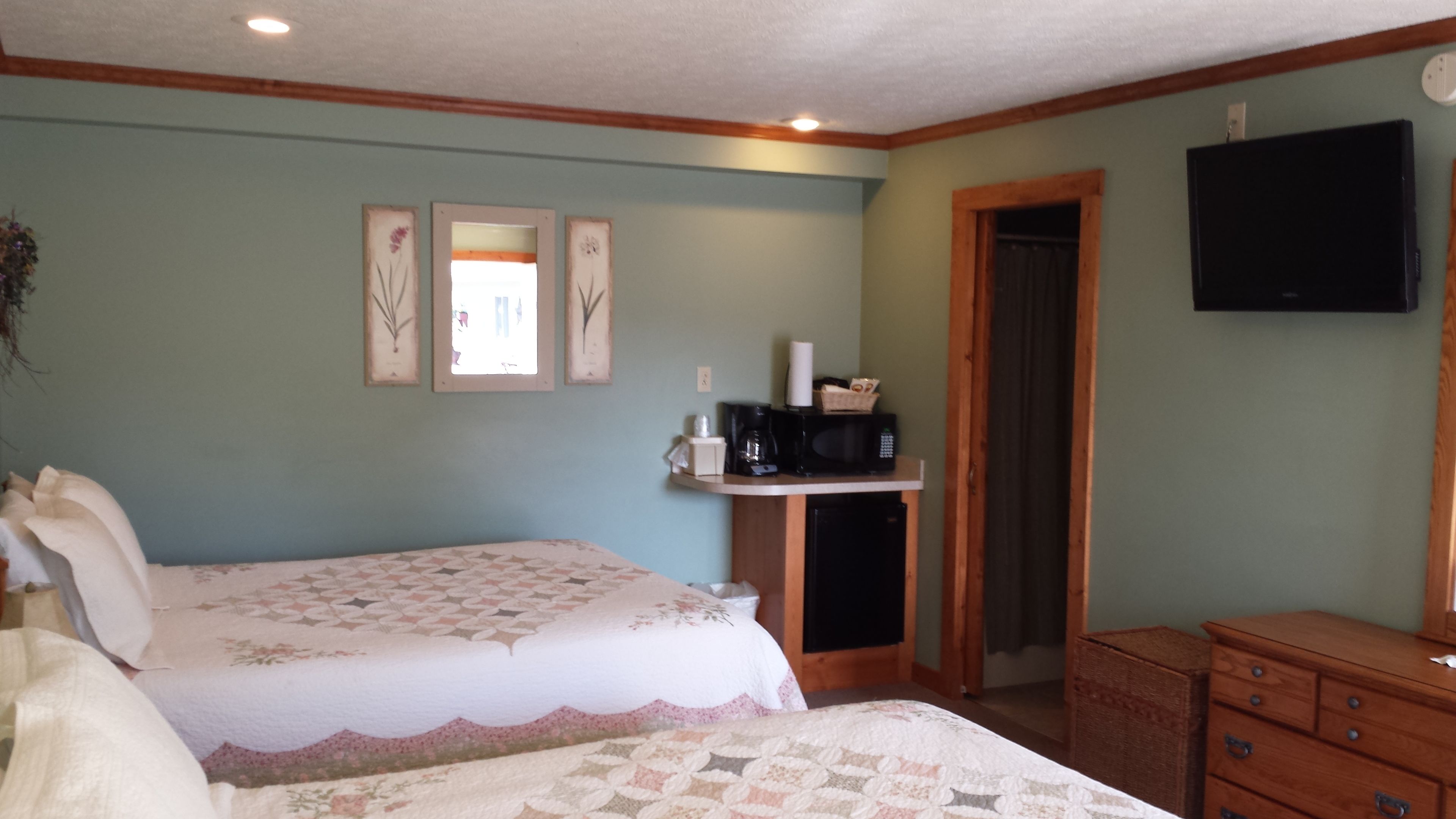 A bedroom with a bed, dresser, and a mounted television.