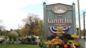 A sign for The Garrett Inn with a swan logo, surrounded by autumn foliage and decorative pumpkins. - The Garrett Inn (Oakland)