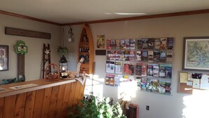 A reception area with a wooden counter, a wall of informational brochures, a hanging lantern, and a framed map. - The Garrett Inn (Oakland)