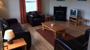 A living room with a fireplace, a television, and a coffee table. - Doolin Village Lodges (Doolin)