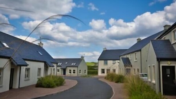 A residential street with houses having sloped roofs and a paved road. - Doolin Village Lodges (Doolin)