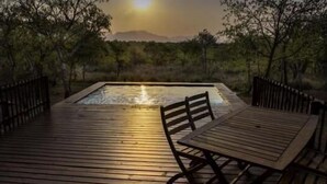 An outdoor wooden deck with a pool, surrounded by trees and a mountain view. - Lion Tree Top Lodge (Hoedspruit)