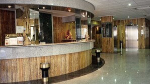 A hotel reception area with a curved counter, marble flooring, and a modern interior design.