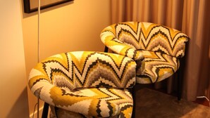 Una habitación con dos sillones estampados, una lámpara de pie blanca y un cuadro enmarcado en la pared.