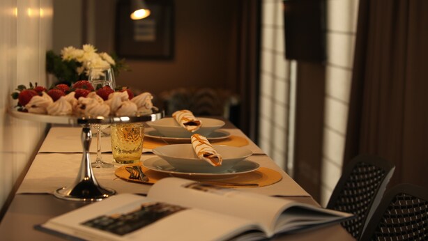 Una mesa de comedor con una cerveza, platos de comida y un libro.