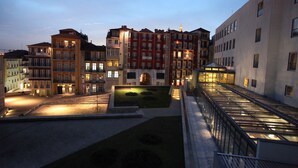 Un edificio residencial de varios pisos con balcones, un patio con fuente de agua y barandilla de vidrio moderna.