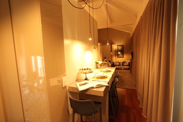 A dining area with a table set for two, a book on the table, and a chair.