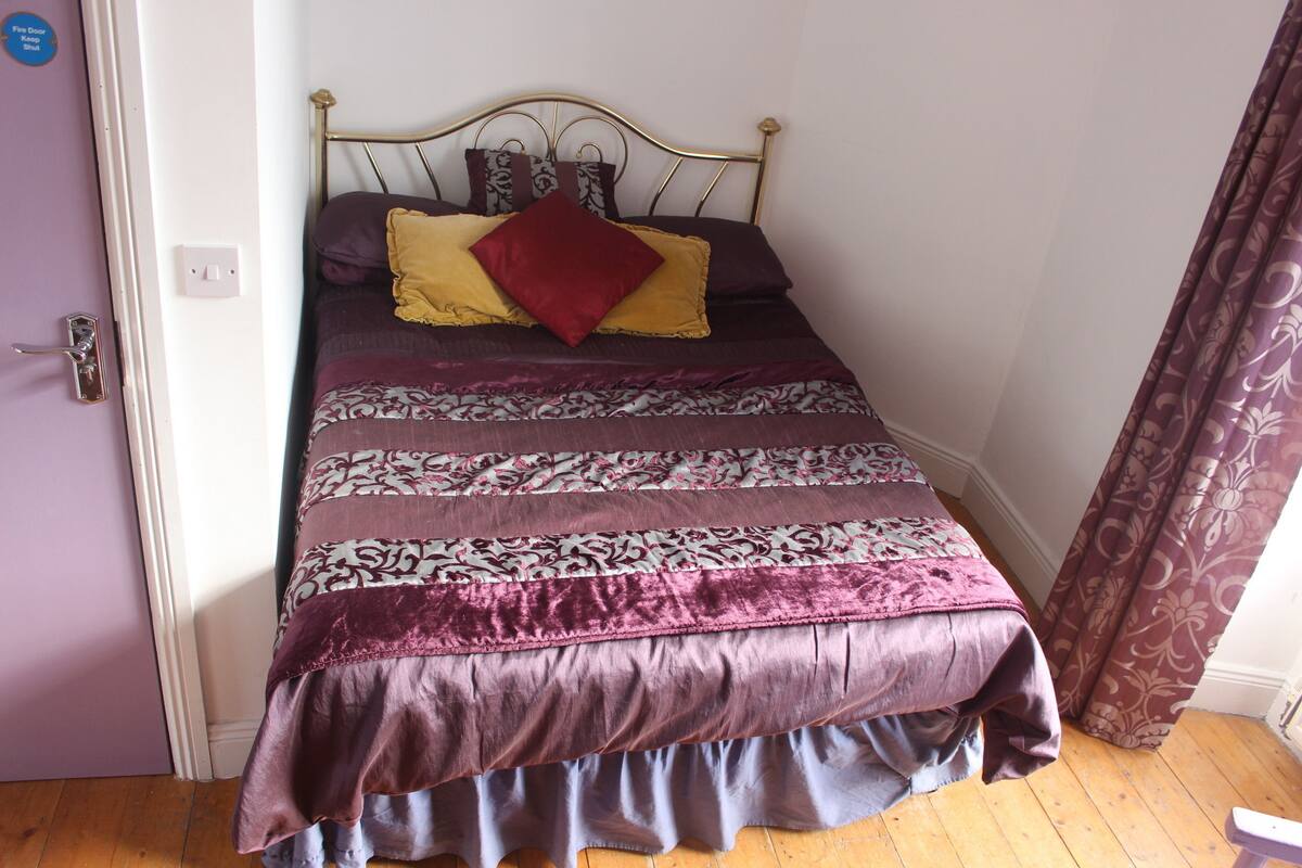 A bed with a patterned bedspread, a headboard, and a door with a handle.