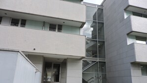 Un immeuble à plusieurs étages doté d’une architecture moderne, caractérisé par une façade en verre et un escalier menant à l’entrée.