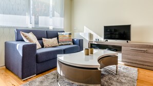 Un salon moderne avec un canapé, une table basse et un téléviseur.