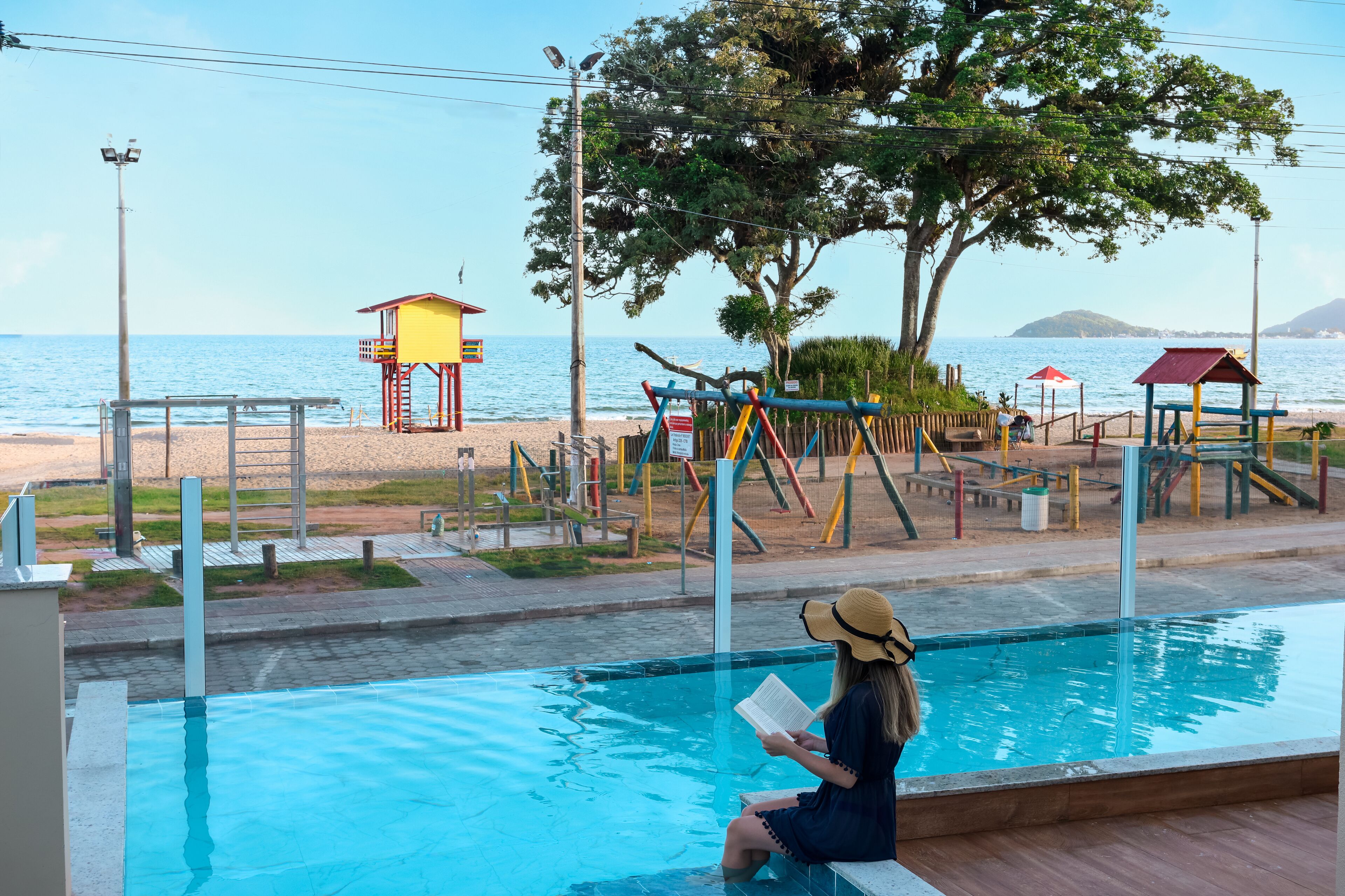 Zona de piscina con vistas a la playa y una torre de salvavidas.
