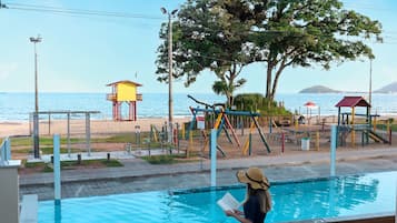 Zona de piscina con vistas a la playa y una torre de salvavidas.