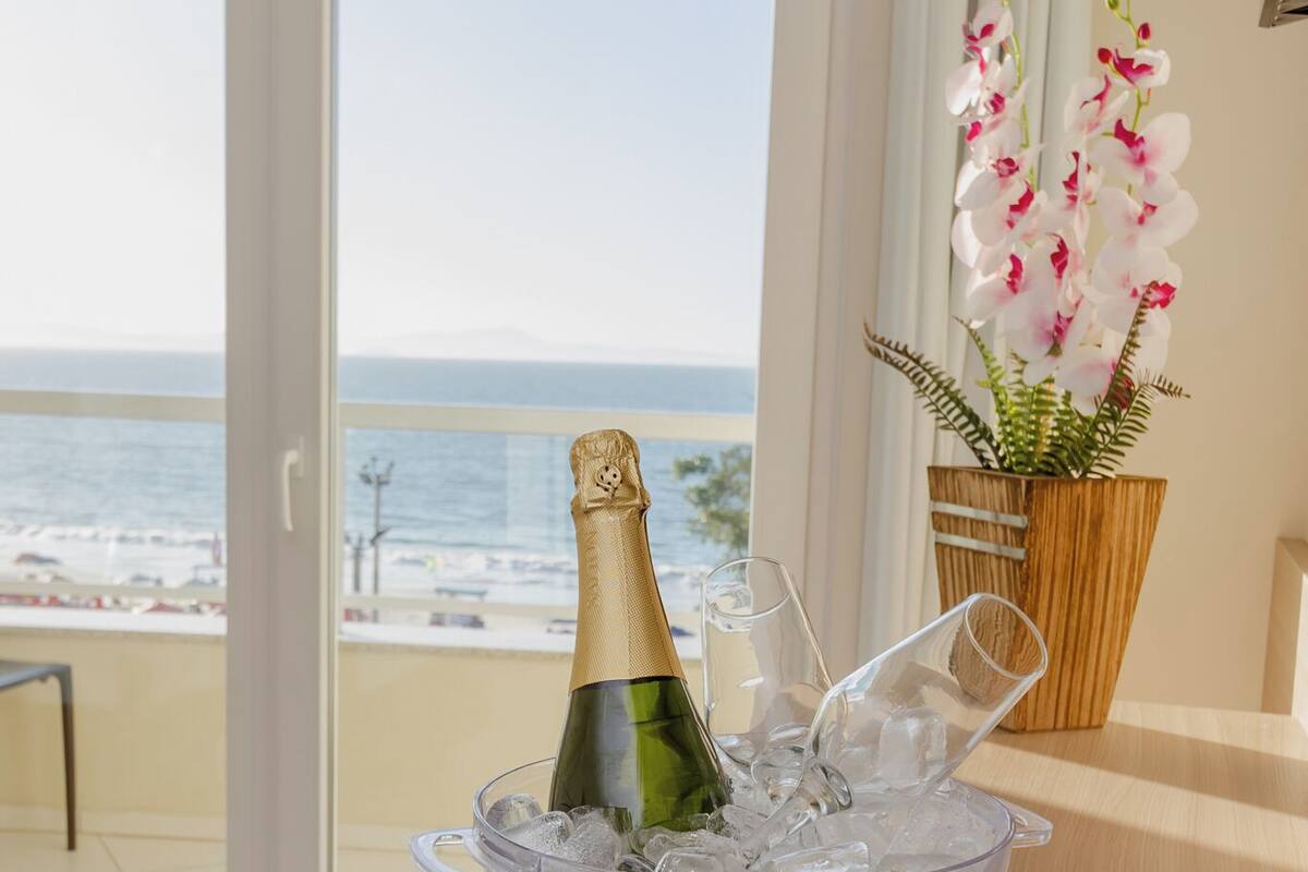 A balcony with a table holding a champagne bottle in ice, a wooden chair, and a potted orchid.
