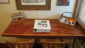 A wooden table with a framed drawing, a welcome brochure, and a basket with items. - Cupola Inn Bed & Breakfast (Nora Springs)
