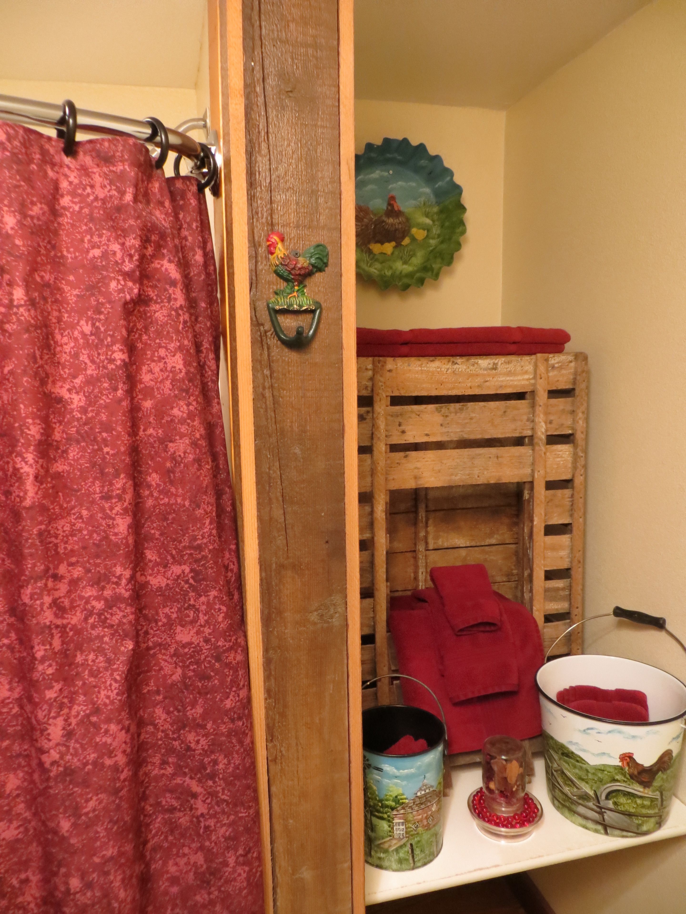 A bathroom with a wooden bunk bed, a red towel, and a shelf with a canister and a glass jar.