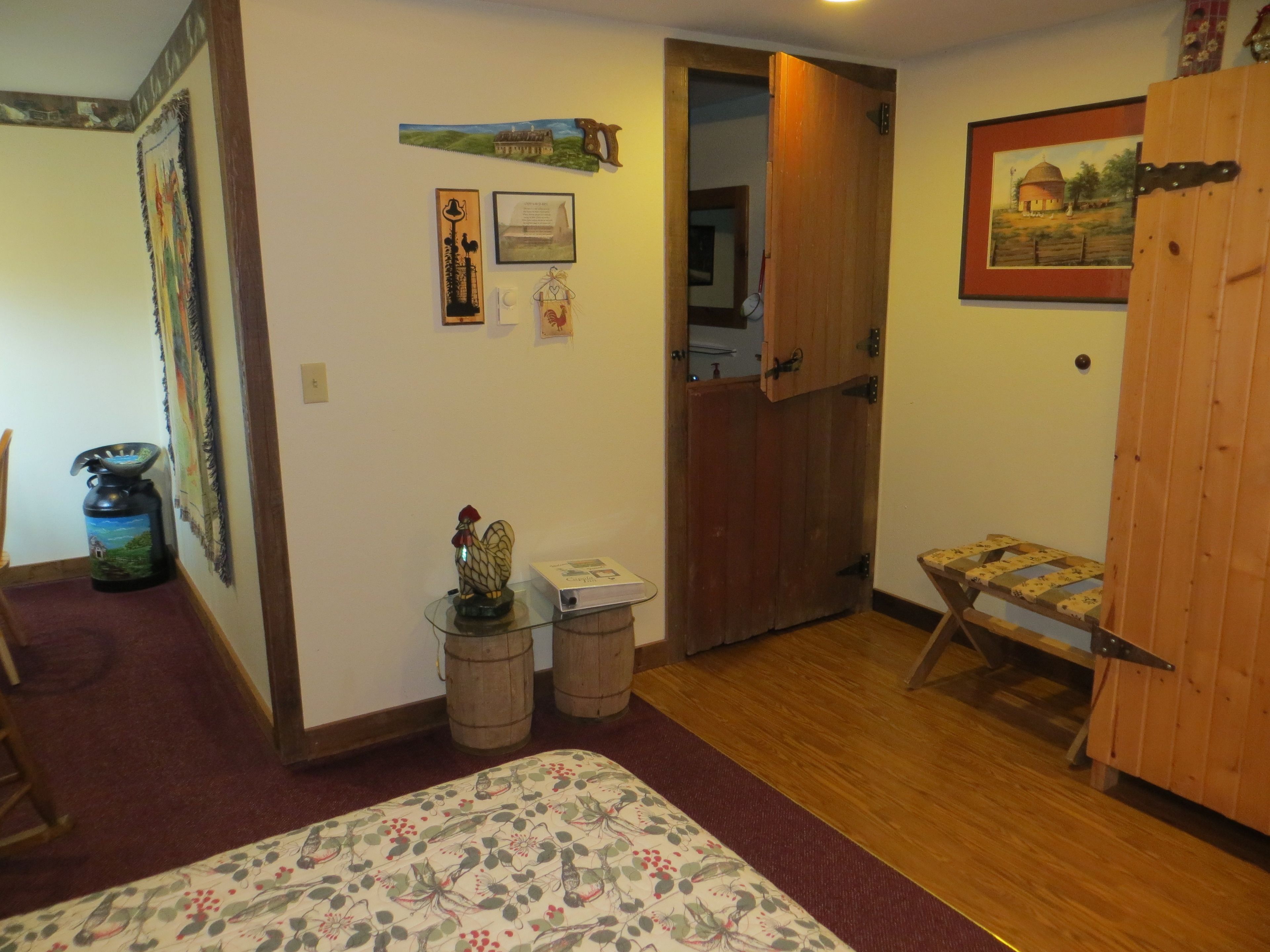 A room with a bed, a wooden door, a small table with a decorative item, and a framed picture on the wall.