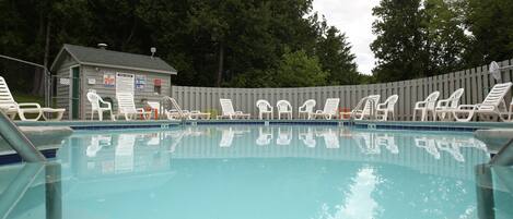 A swimming pool with lounge chairs and a small building with signs.