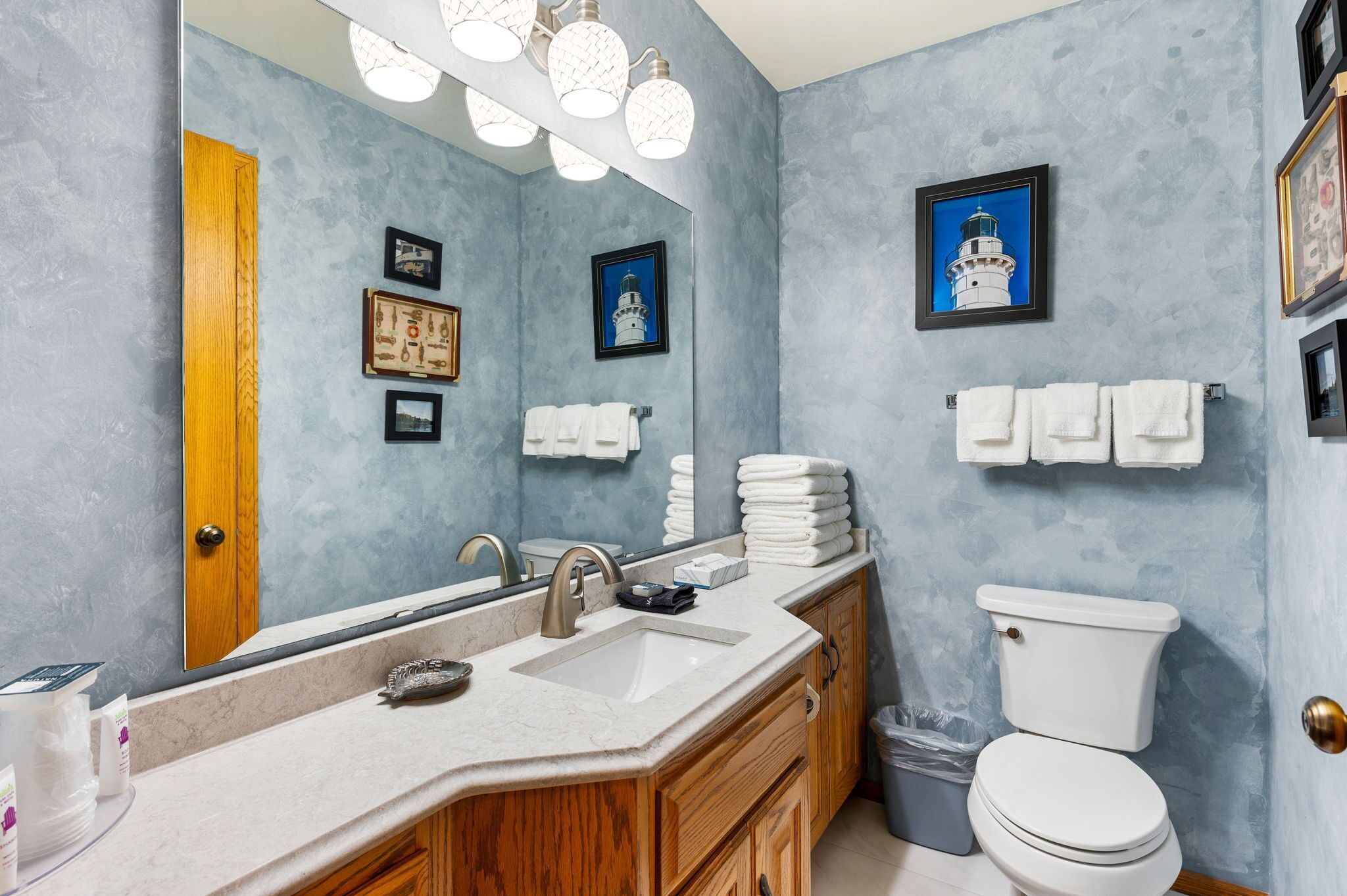 Une salle de bain avec un lavabo en marbre, des meubles en bois, des toilettes blanches et un grand miroir.