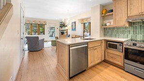 A modern kitchen with wooden cabinets, a dishwasher, a microwave, and an oven. - Evergreen Hill Condominiums (Fish Creek)