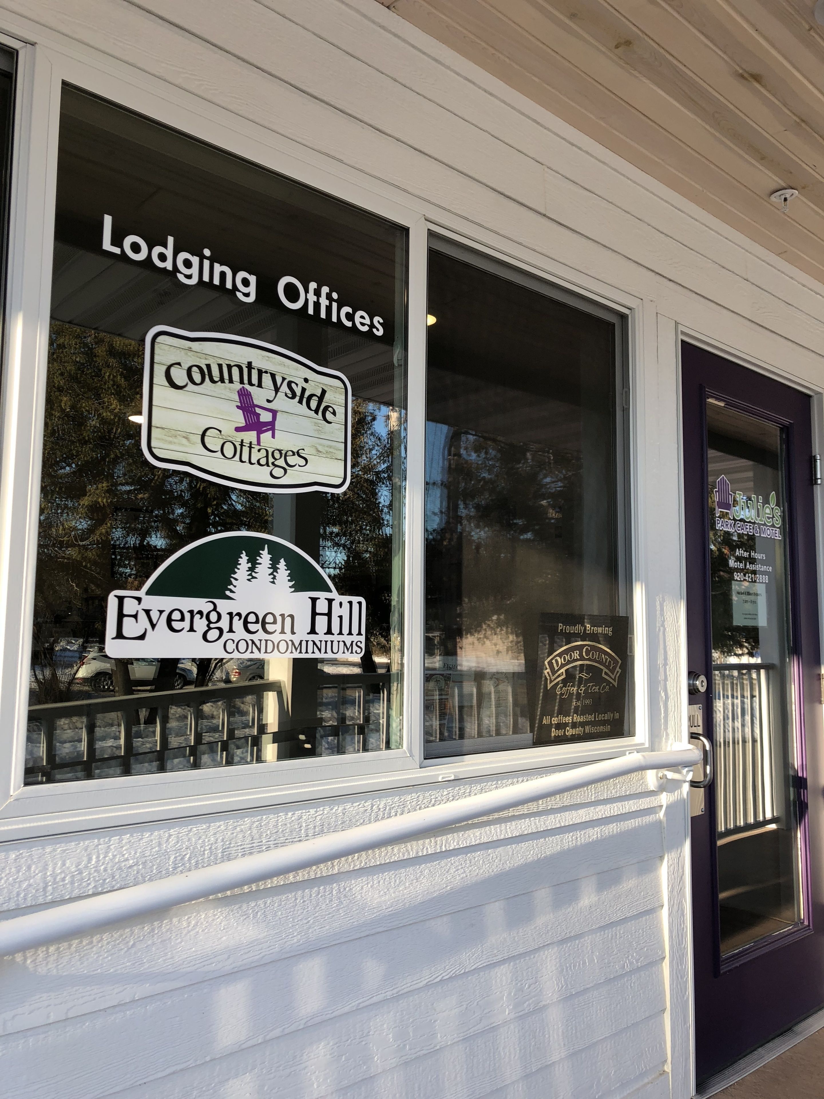 A window with signs for 'Countryside Cottages', 'Evergreen Hill Condominiums', and 'Door County Coffee & Tea Co.'.