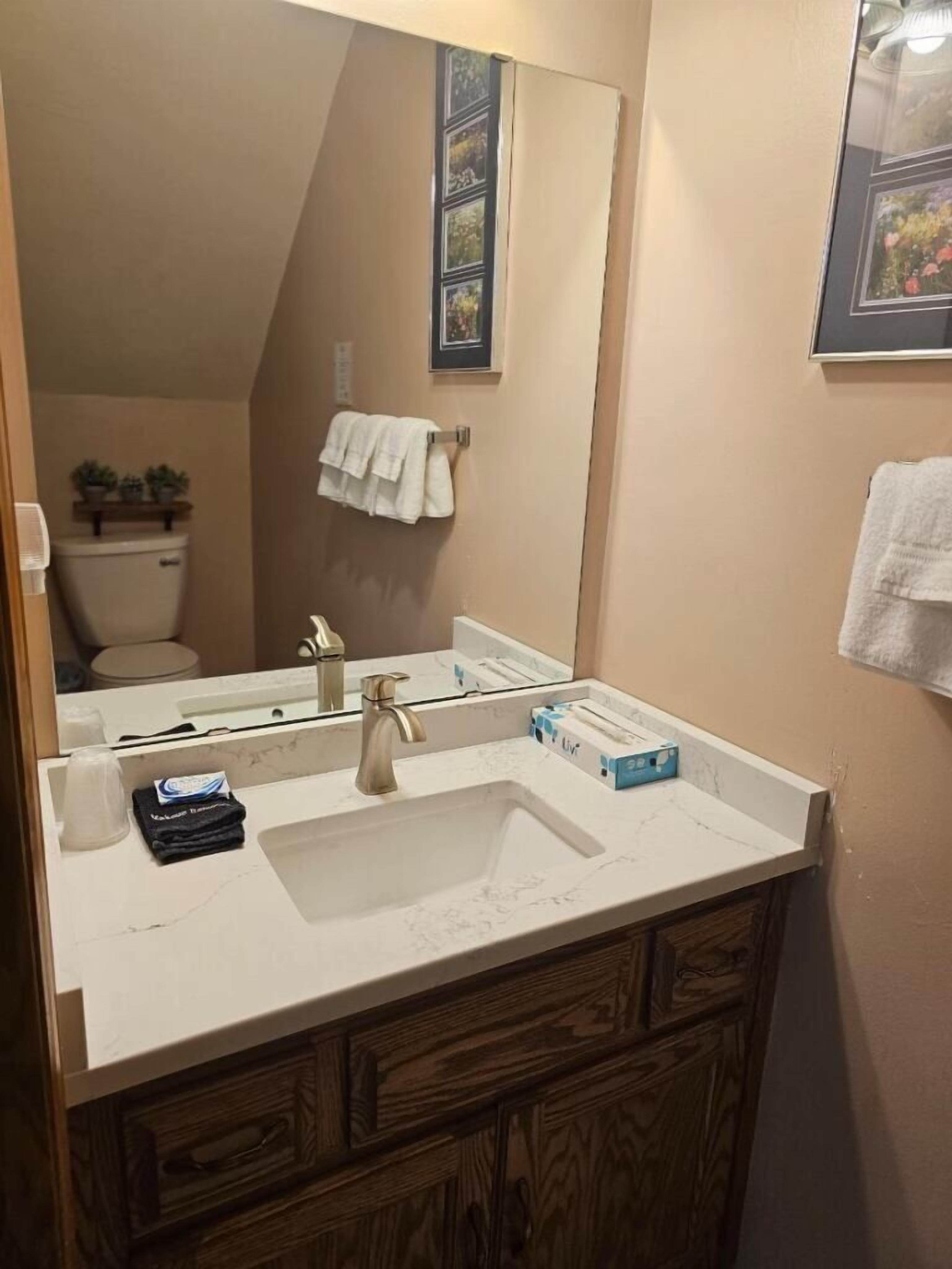 A bathroom with a white sink, a mirror, and a wooden cabinet below.