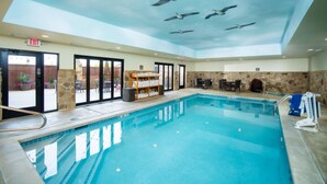Una piscina interior con techo transparente y pared de piedra.