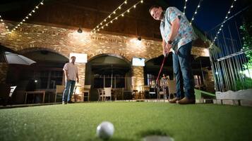An outdoor patio area with brick walls, string lights, and a putting green.