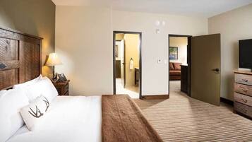 A hotel room with a bed, bedside lamp, dresser, and a television.