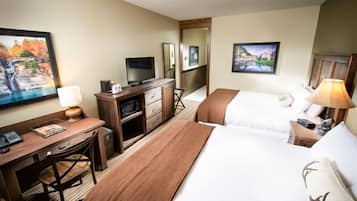 Habitación de hotel con cama, escritorio, silla, televisor y obras de arte en las paredes.