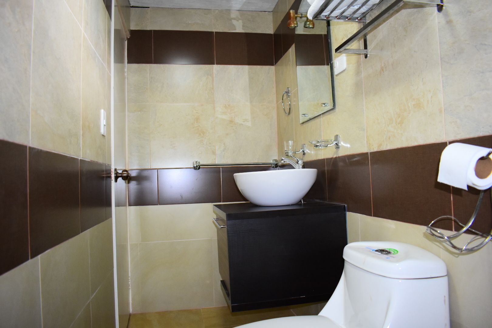 Een badkamer met een witte wastafel, een zwart kastje en een toilet.