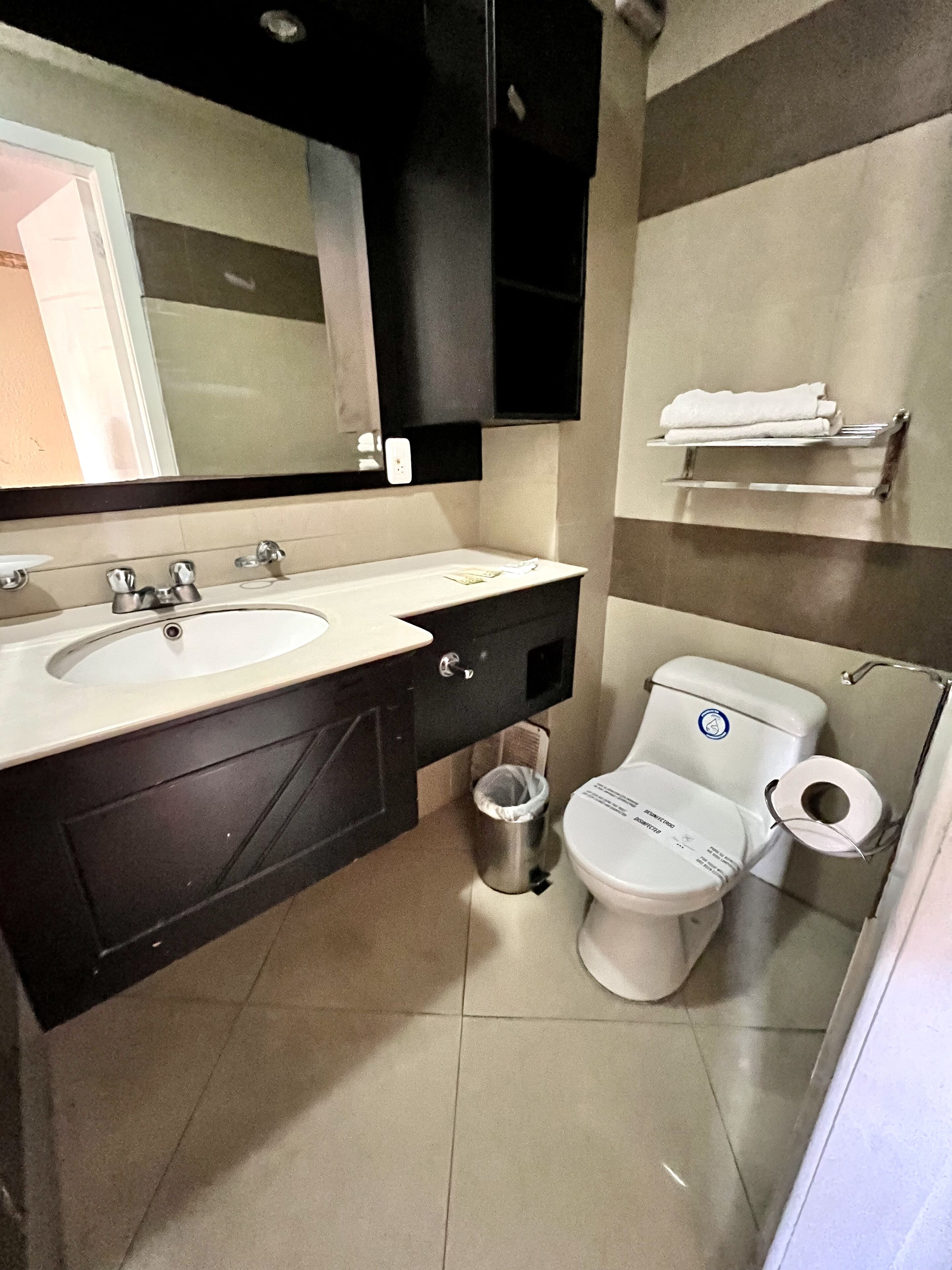 Un baño moderno con tocador de doble lavabo, inodoro y cubo de basura.