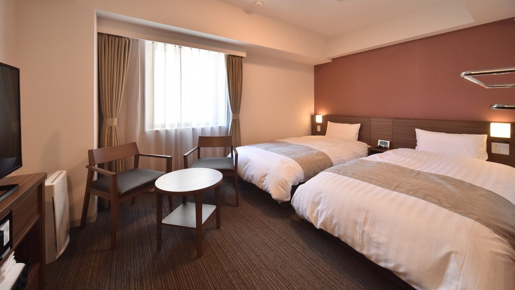 Une chambre d’hôtel avec deux lits, un bureau et une chaise.