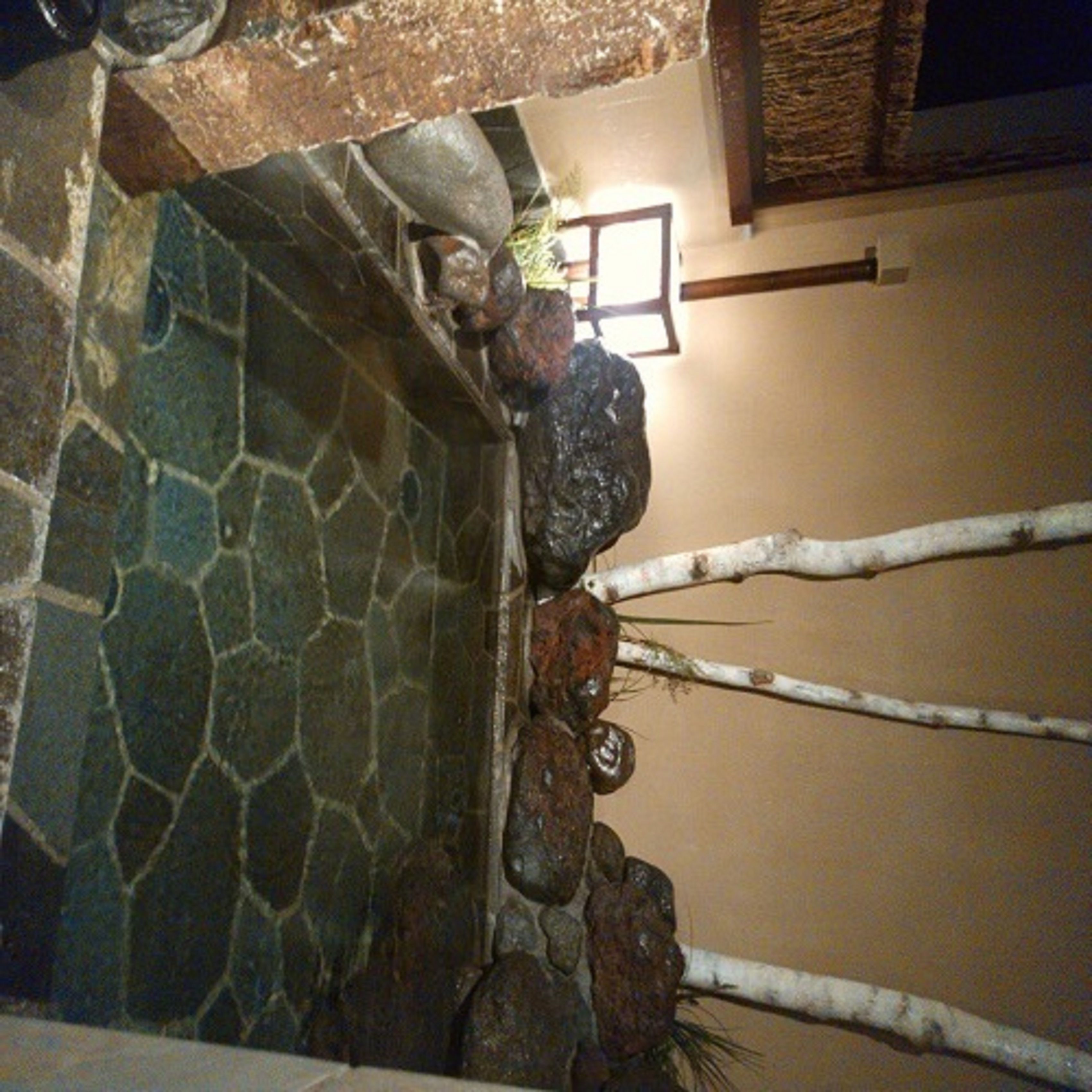 A stone wall with a small water feature and a wooden beam.