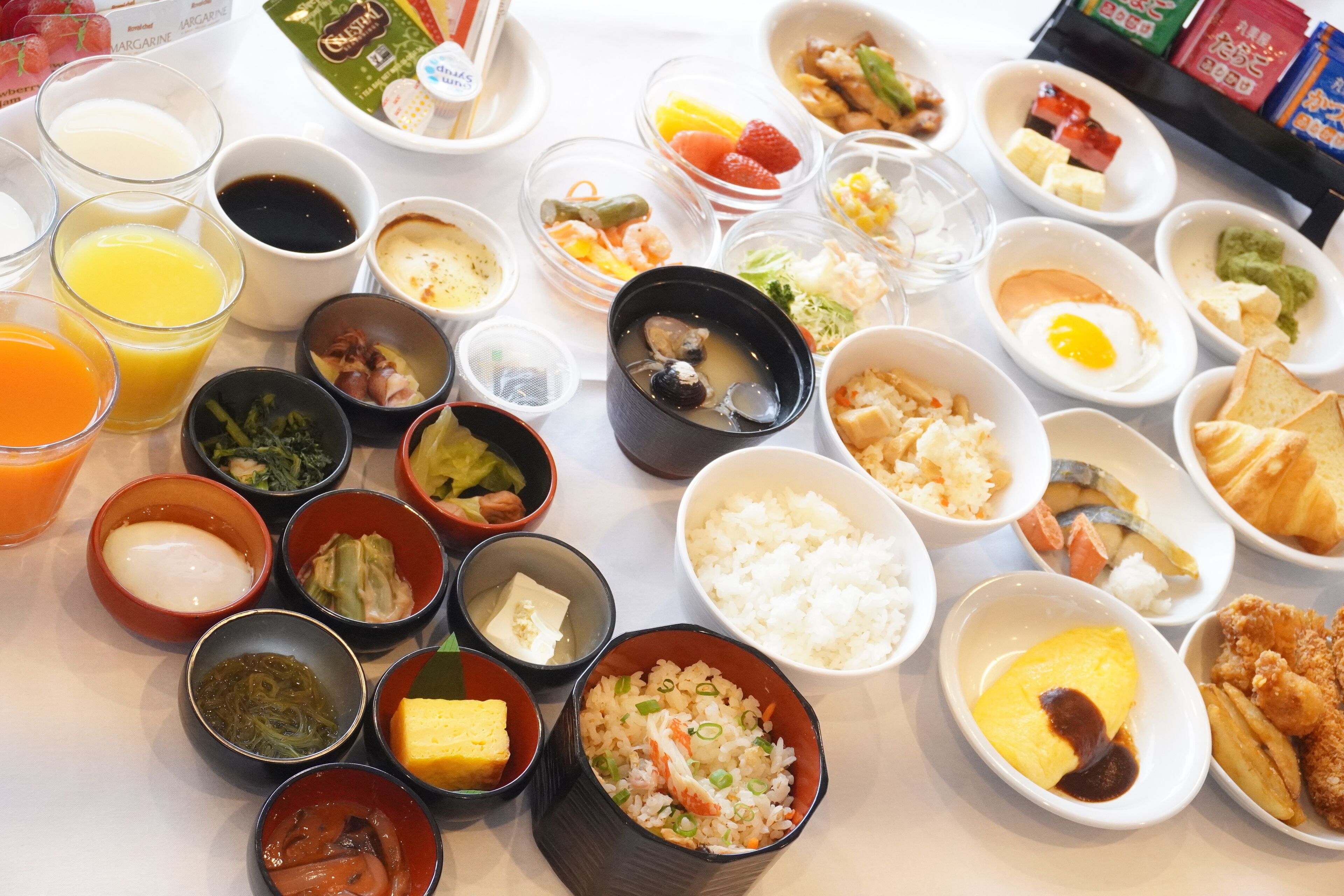 Una mesa con varios platos y condimentos, como arroz, huevos y verduras.