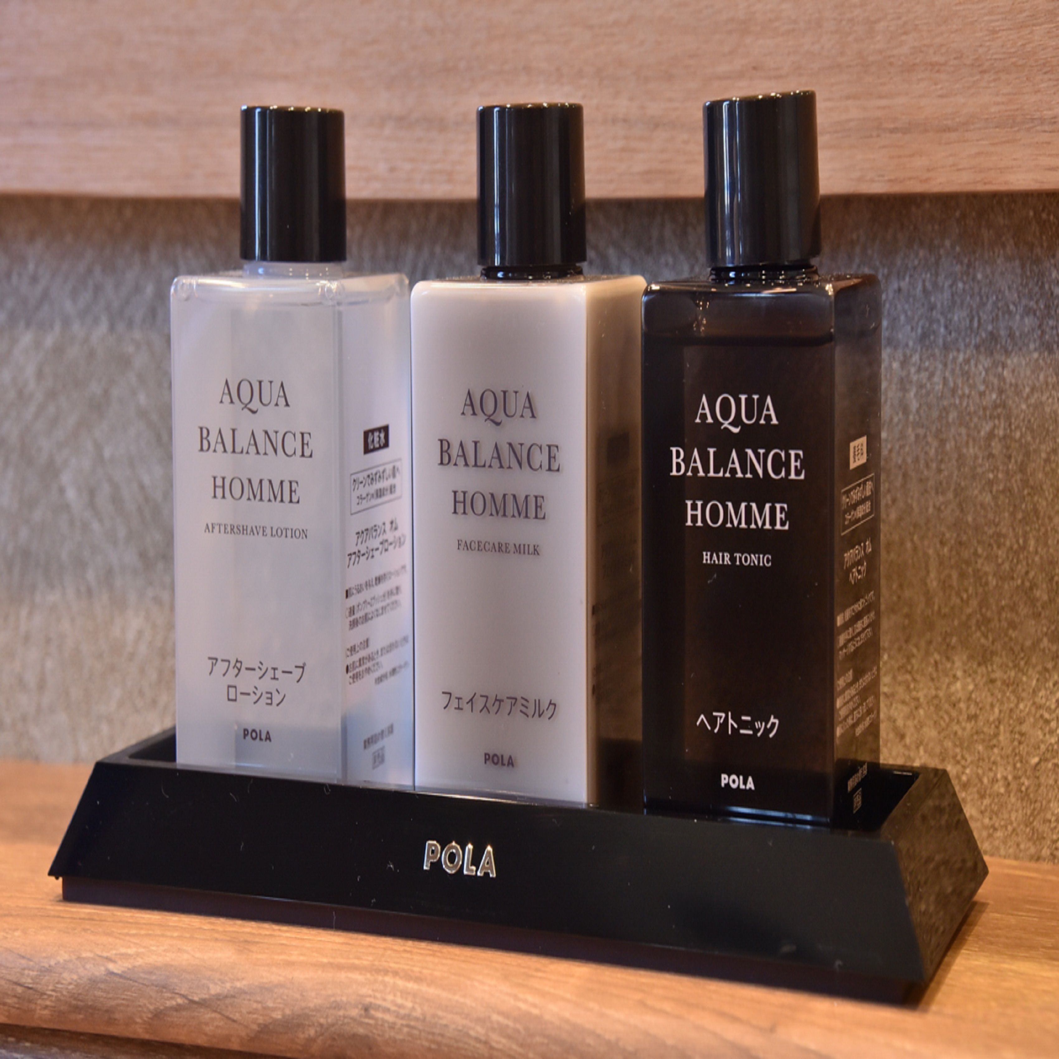 Tres botellas de AQUA BALANCE HOMME sobre un pedestal negro.