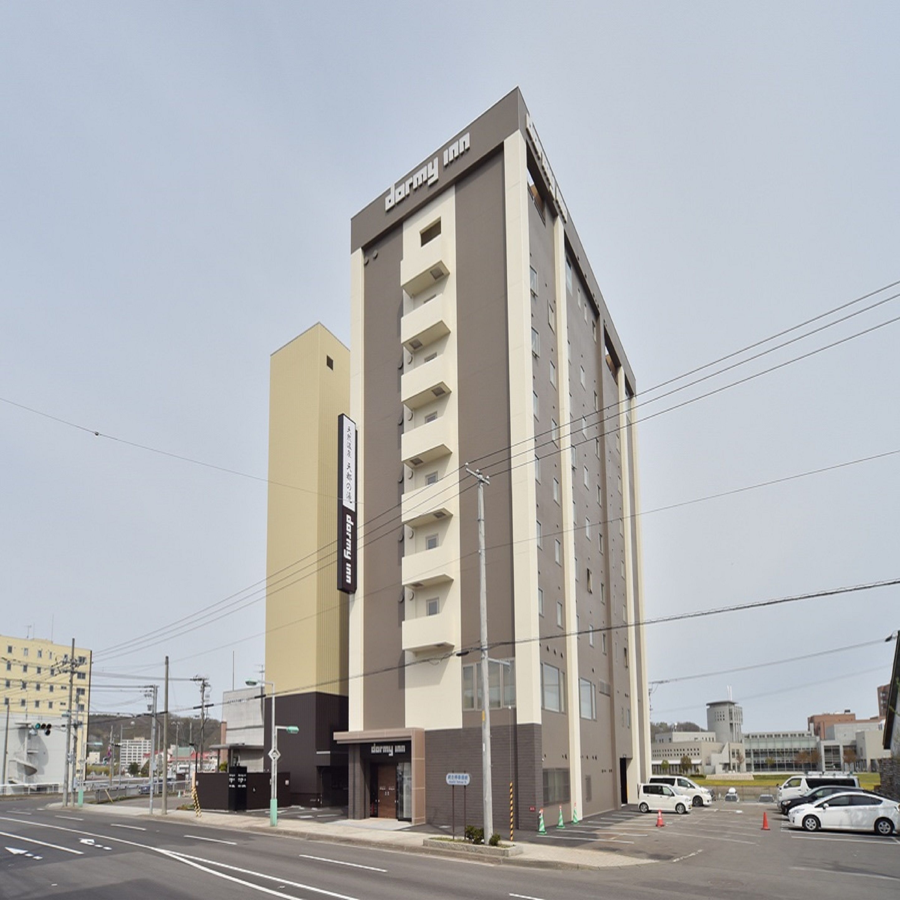 Un edificio de varios pisos con un letrero que dice "dormy inn" en la fachada.