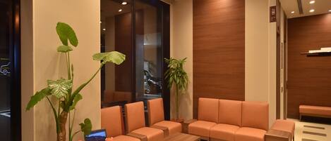 A modern waiting area with a sofa, coffee table, and potted plants.
