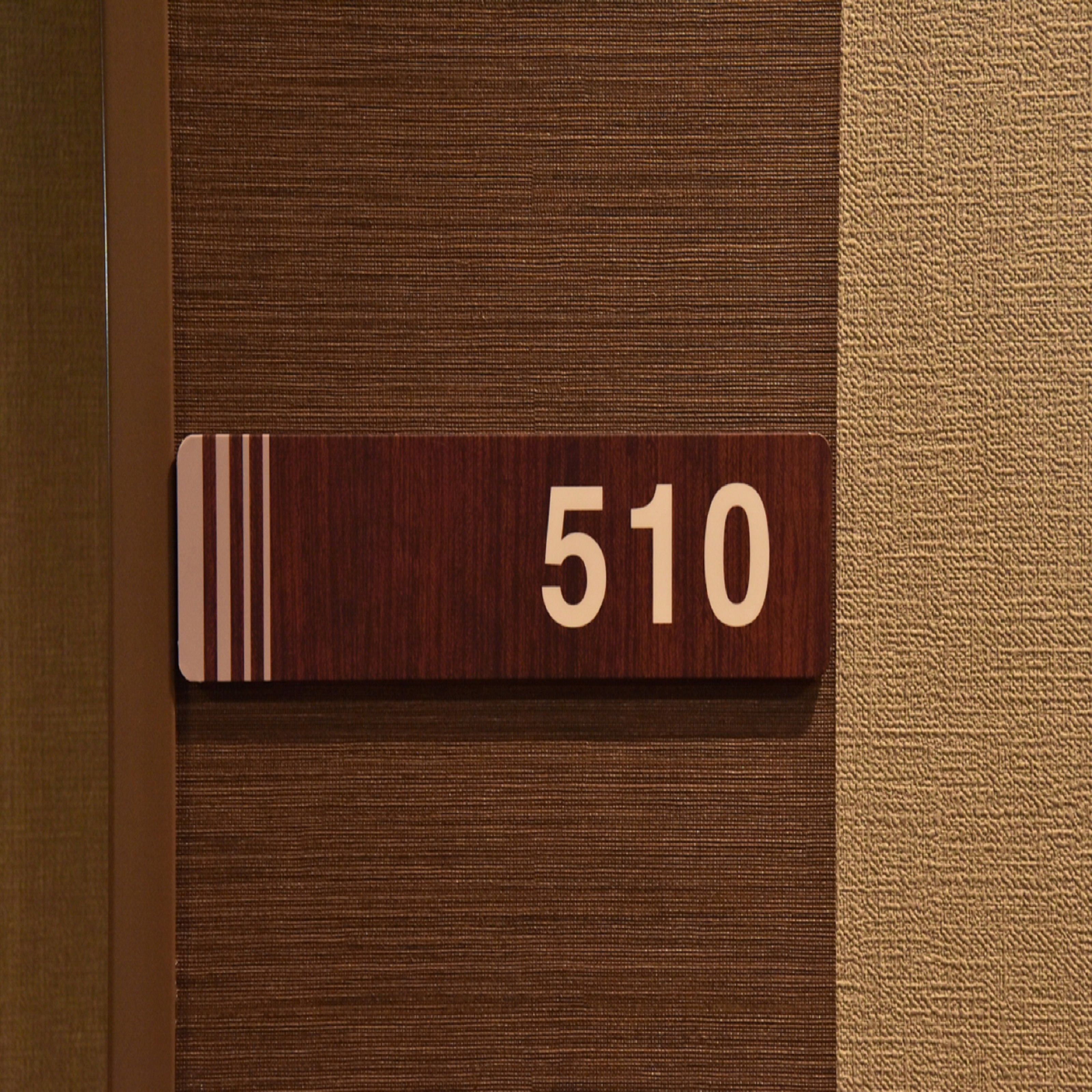 A wooden room number plaque with the number 510 on a textured wall.