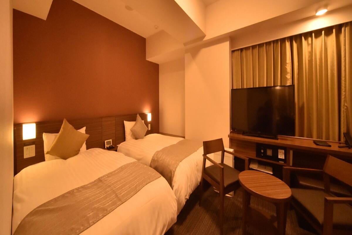 Habitación de hotel con dos camas, un televisor, un escritorio y una silla.