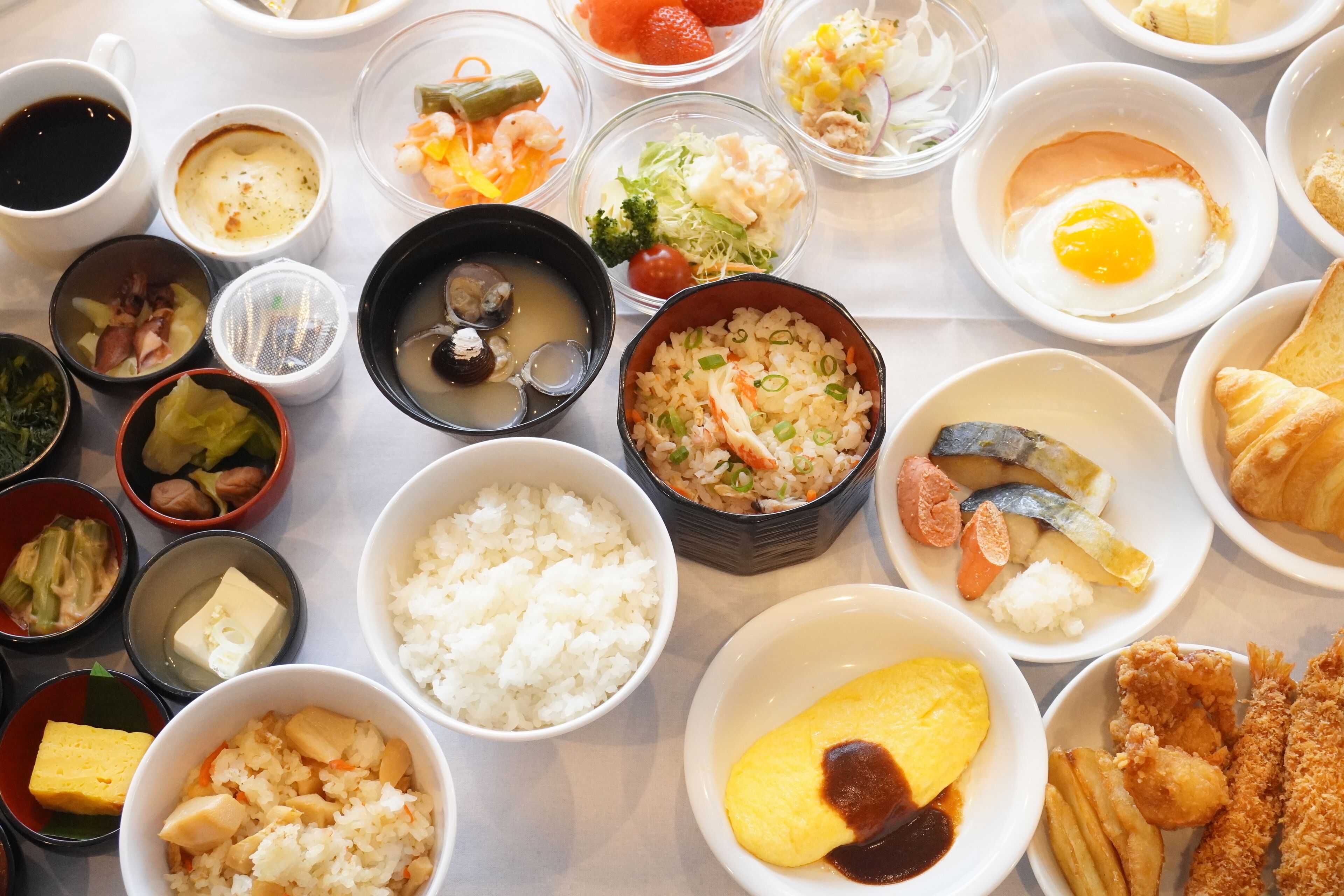 A variety of dishes including rice, eggs, and seafood, arranged on a table.