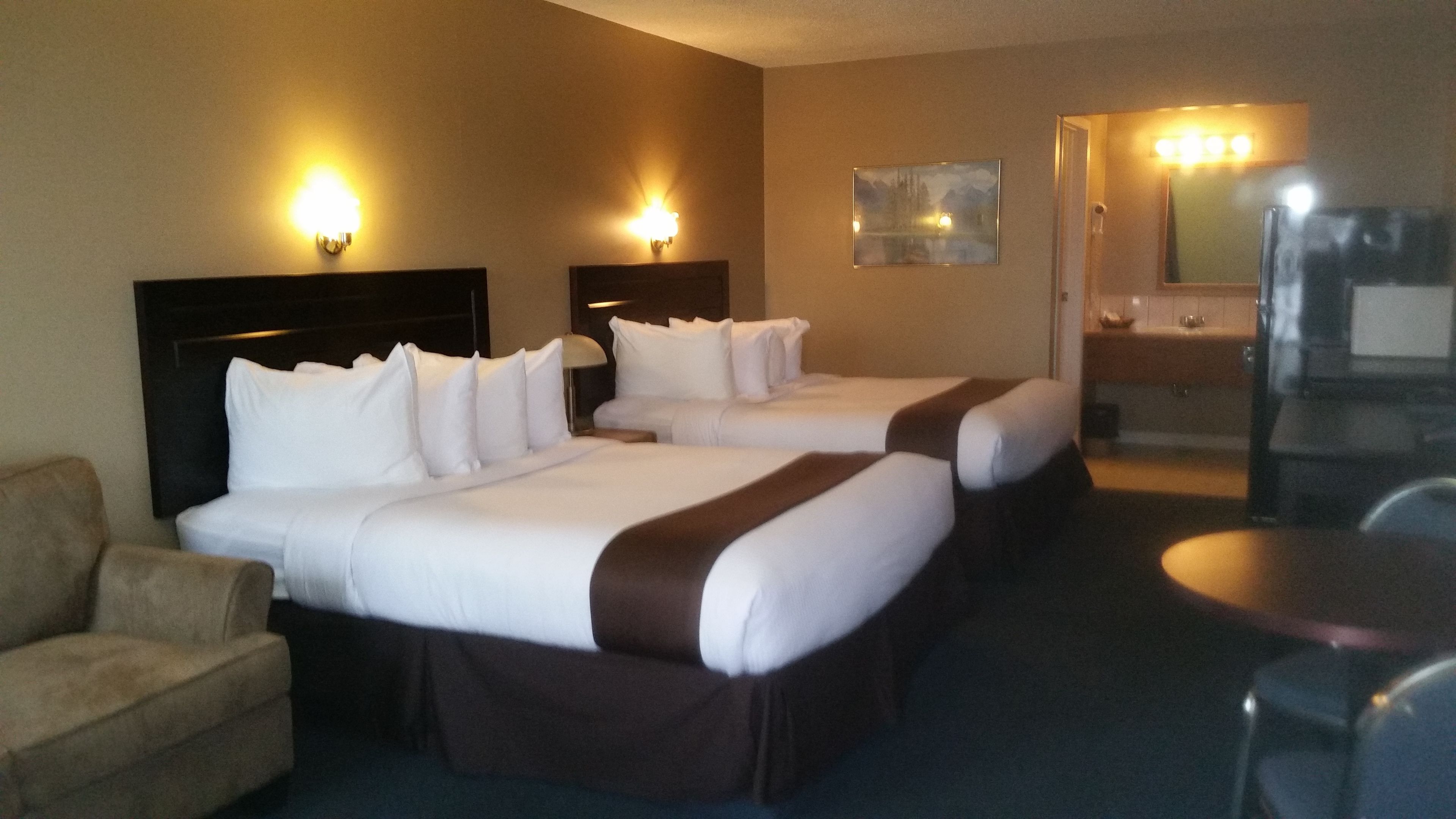 A hotel room with two beds, a sofa, a desk, and a mirror.