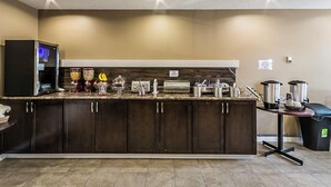 A modern kitchen with dark cabinets, a granite countertop, and various appliances including a coffee maker, toaster, and blender. - Chinook Country Inn (Sundre)