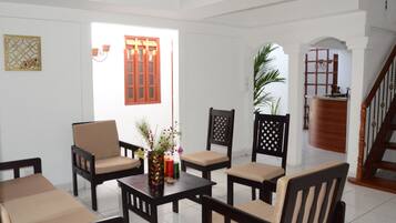 Um quarto com interior branco, uma escadaria de madeira e vista para o exterior através de uma janela com porta vermelha.