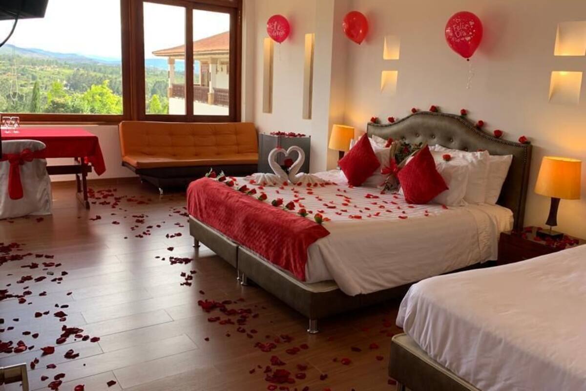 Une chambre d’hôtel avec un grand lit, un lit plus petit, un canapé et une table à manger.